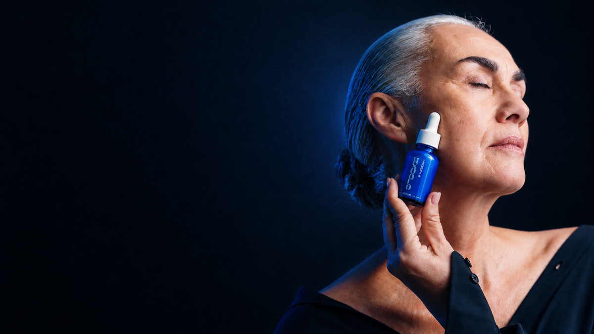 Woman with silver hair, eyes closed, holding a bottle of EXOGLO Serum to her cheek