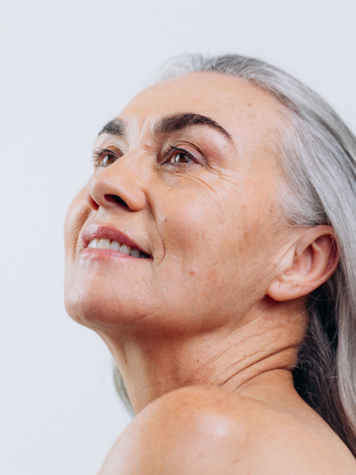 A grey-haired woman smiling and looking upwards